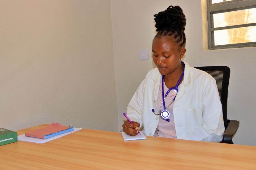 A clinician writing notes at her desk